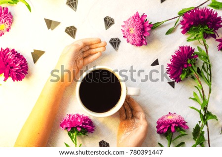 hot coffee. hands holding a mug. flowers and diamonds. view from above.