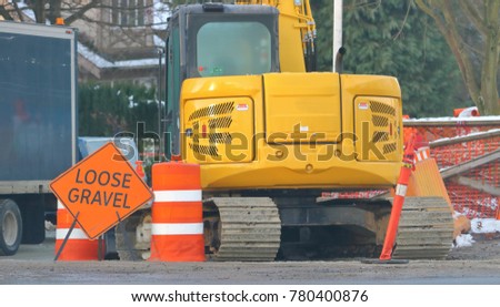 A sign stands on a construction site warning that the area has loose gravel. 
