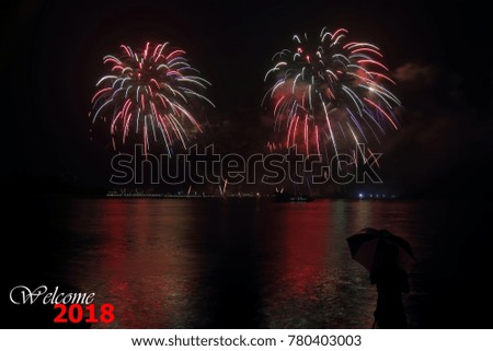 Beautiful firework display for celebration on the river with a colorful reflection on the water surface with a text Welcome 2018.