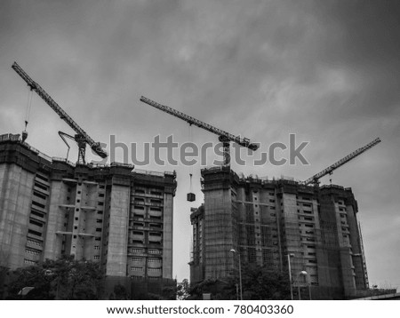 Hoisting cranes and building activity. Construction site background. Tower crane near new multi-storey building.