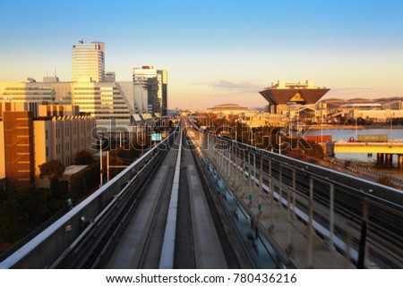On the rail of the Yurikamome line of Tokyo, approaching the Tokyo Big Sight station, during sunset.