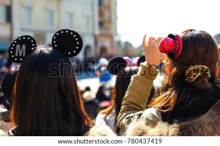 Young women wearing cute hair clips and watching costume dance performance in park.