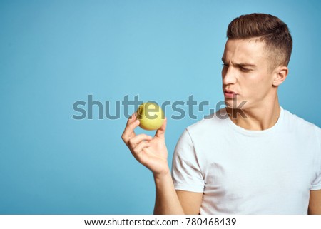  a man looks at an apple on a blue background                              
