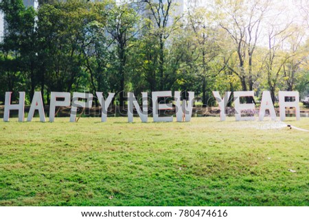 a outdoors celebration decoration sign with "Happy New Year" text board in the middle of the grass field in the mid city garden