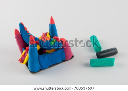 Creative colored clay figures of dragon, castle and play dough sticks on white background