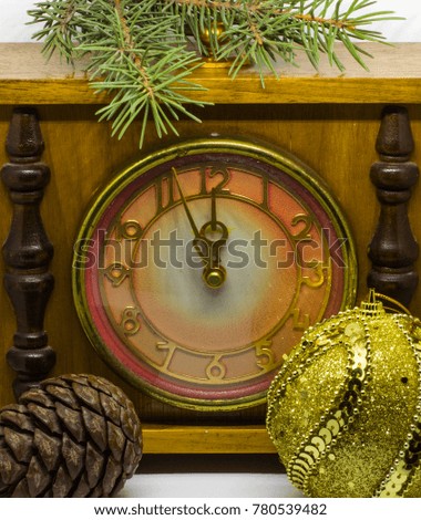 Ancient clock, a branch of a Christmas tree, a Christmas tree and a Christmas tree toy. A golden ball. Without five midnight.