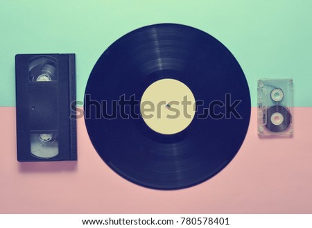 Retro entertainment from the 70s. Vinyl plate, video cassette, audio cassette on a colored pastel background. Top view.