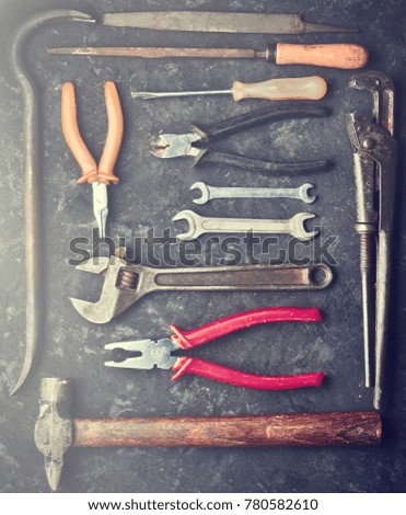 Many working tools on a black concrete table. Nippers, file, pliers, scrap, hammer, wrench, screwdriver. Top view. Flat lay.