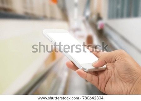 Hand holding with smartphone in the shopping mall.