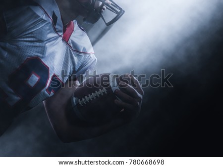 American football player holding ball while running on field at night