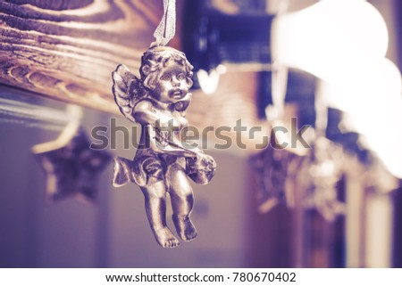 A toy of an angel hangs on the background of a mirror. Amur. Valentine's Day. Blur.