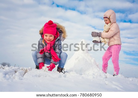 Two grill making snowman. Looking at camera.  Space for copy.