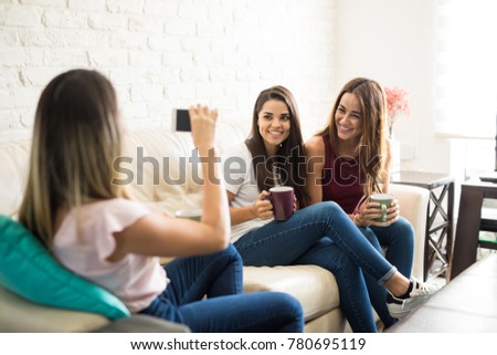Three cute female friends having some fun together at home and taking photos to each other