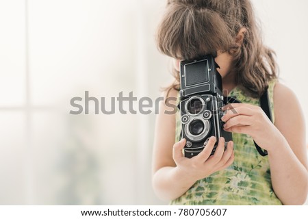 Cute photographer girl holding a vintage twin-lens reflex camera