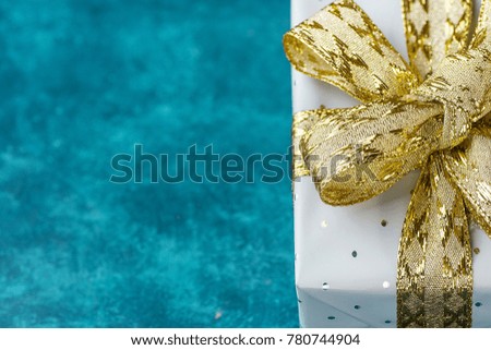 Elegant Gift Box Wrapped in Grey Silver Paper with Polka Dots Golden Ribbon on Blue Turquoise Background. Valentine Birthday Mother's Day Christmas New Years Presents Shopping Sale. Copy Space