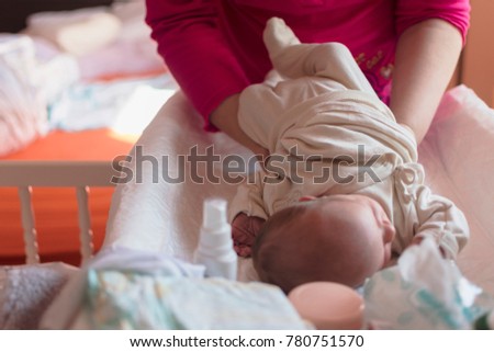 the mother replaces the babies' nappies on the baby on the table provided for it