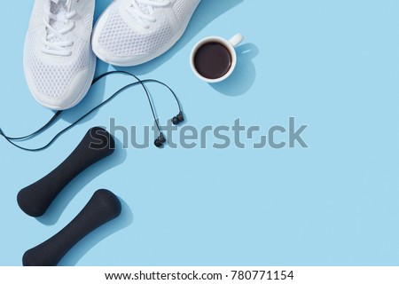 Sports flat lay with coffee, dumbbells, sneakers and earphones on blue background Royalty-Free Stock Photo #780771154