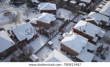 Aerial drone photo, top down, of suburban houses in Oakville, Ontario, Canada everything is white and covered with snow in the sunshine.