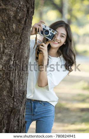 Attractive Asian woman using retro camera with smiling, Woman using camera at outdoor place.