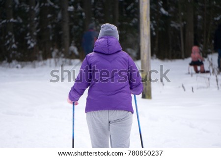 Girl skiing during snowfall weather ski resort Skier wears a blue winter coat, purple hot pants, blue shorts and white gloves. The tree covers the snow
