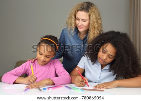 mom watches as her daughter drawing with crayons
