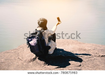 Happy Asian woman backpacker using smartphone shooting view of nature winter season,Relax time on holiday concept travel,selective and soft focus,tone of hipster style