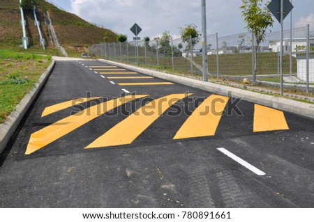 Speed hump ahead with yellow stripes.  