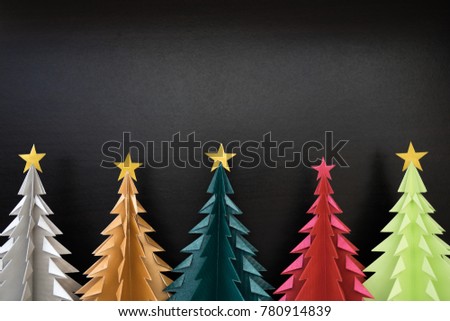 Colorful Origami Christmas Trees with black wooden background.