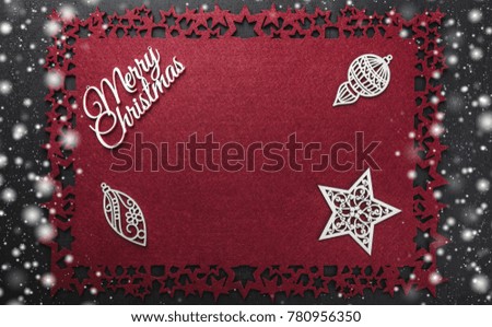Merry Christmas inscription, with some handmade wooden toys and star, on red cloth snowy, snow, background, view from above with free space for text writing.