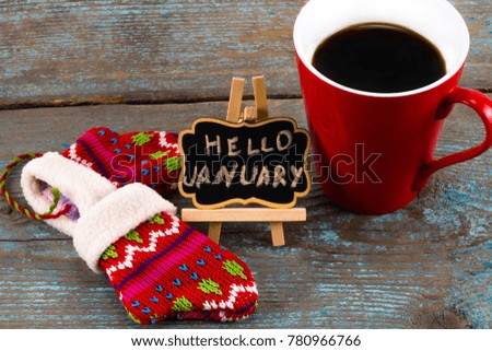 Concept HELLO january message on blackboard with a Cup of coffee and mittens.