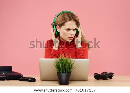  woman in headphones working behind laptop on pink background, technology                              