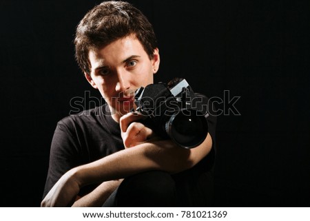 Photographer with film camera on black background. Horizontally framed shot.