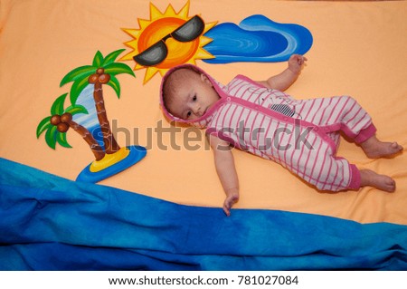 Creativity. Top view on child laying between drawn palm, sun, cloud on orange, blue background