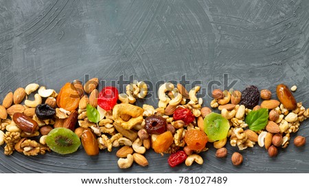 Various dried fruits and mix nuts on a gray stone or slate background.  The concept of the Jewish holiday Tu Bishvat. Flat lay, top view with copy space. Royalty-Free Stock Photo #781027489