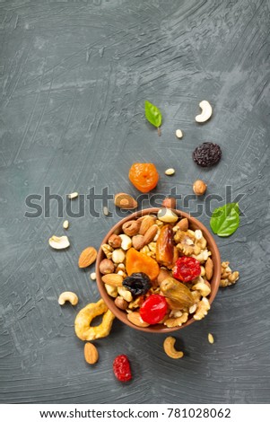 Various dried fruits and nuts in a ceramic bowl (walnut, cashew, almonds, pine nuts, hazelnuts) on a gray stone or slate background. The concept of a healthy dessert. Flat lay, top view. Royalty-Free Stock Photo #781028062