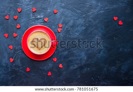 Cup of coffee with heart shape on dark blue background for Valentine's Day greeting card. Top view. 