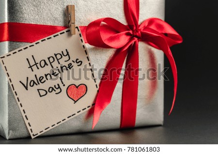 Gift in silver packaging with red ribbon and greetings with Valentine's day. Copyspace