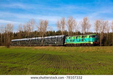 Passenger train hauled by the diesel locomotive passing the sunny landscape