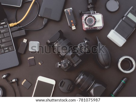 top view of work space photographer with digital camera, flash, camera cleaning kit, memory card, external harddisk, USB card reader and camera accessory on black table background