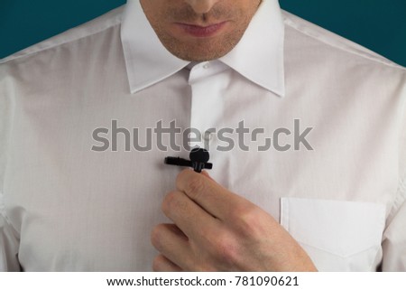 A man fixes lavalier microphone, preparation for interview