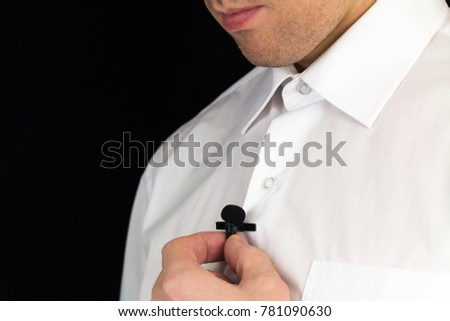 Man holds lavalier microphone, preparation for interview