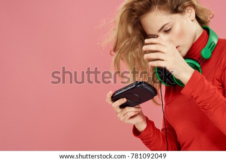  woman plays the console on her headphones on a pink background                              
