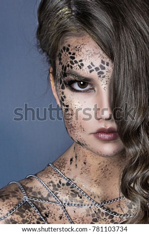 close up portrait of beautiful serious girl with long hair and chain. black face painting . professional creative makeup