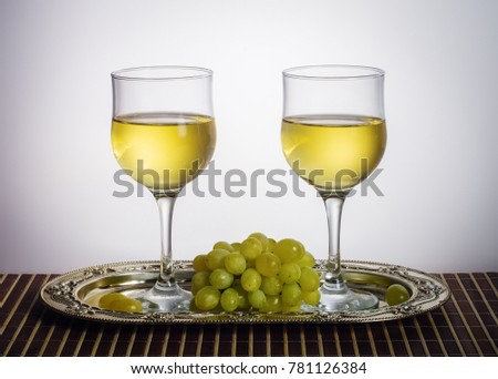 Two glasses of white wine and a bunch of green grapes on a metal dish / Photo taken in a personal photographer studio