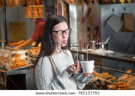 Young caucasian girl eating spicy asian food near street food booth in Hong Kong.  Royalty-Free Stock Photo #781137793