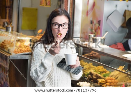 Young caucasian girl eating spicy asian food near street food booth in Hong Kong.  Royalty-Free Stock Photo #781137796
