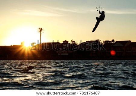 Recreational water sports: kitesurfing. Kiteboarding sportsman jumping high in the sky on windy day. Extreme sports action with wind and water. Healthy active lifestyle.Summer fun adventure and hobby.