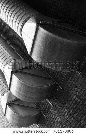 Outdoor ventilation tubes mounted on brick wall, black and white photo