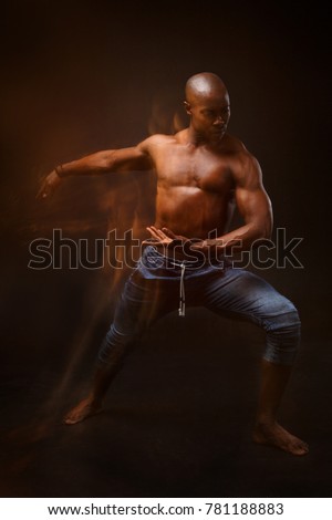 Dancing black man on a black background with a mixed light.