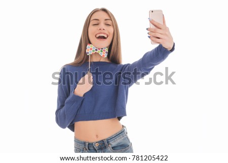 Beauty funny teenage girl with paper bow tie on stick making selfie with her cellphone